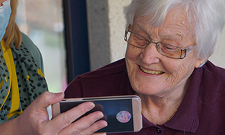 Bild på en äldre kvinna som kollar på en annans persons telefon