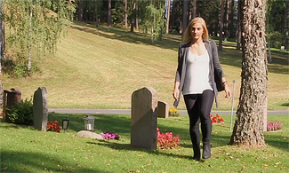 Bild å en kvinna som går på en kyrkogård 