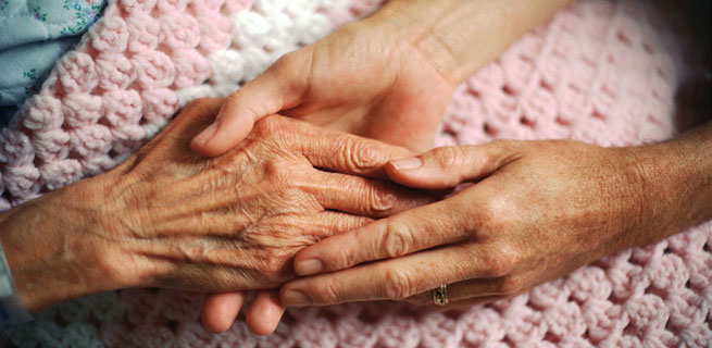 Bild på en person som håller en äldre kvinnas hand
