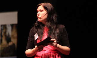 Bild på Mia Berg som står på scen och håller i en bok.