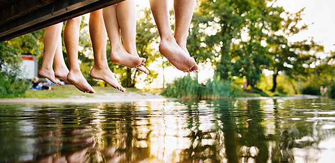 Fötter som dinglar ovanför vattenytan från en brygga