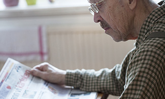 Bild på en äldre man som läser tidningen