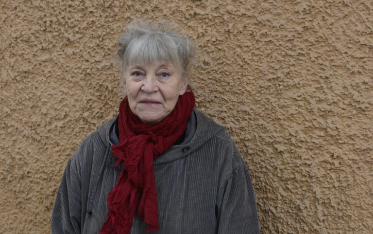 Bild på Ulla Elfving Ekström som står mot en husvägg