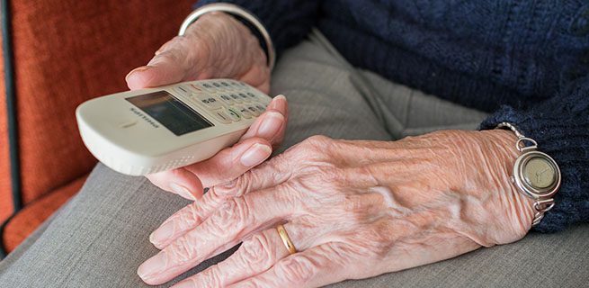Bild på en äldre person som håller i en telefon