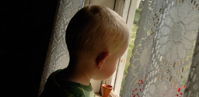 Bild på ett litet barn som kollar ut genom fönstret