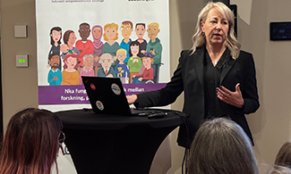 En kvinna står vid ett bord och föreläser