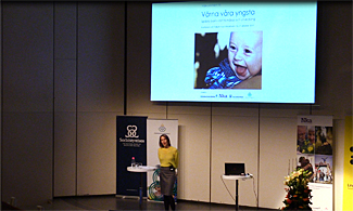 Bild på konferensscenen där en kvinna håller i en föreläsning