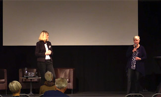 Bild på två kvinnor som står på scen och föreläser