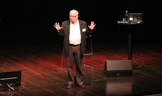 Bild på Ulf Axberg som står på scen och föreläser 
