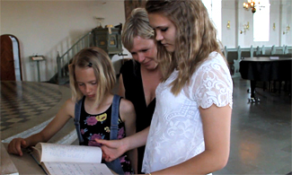 Bild på en mamma och två döttrar som läser en bok.