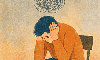 En person sitter på en stol med huvudet lutad i händerna