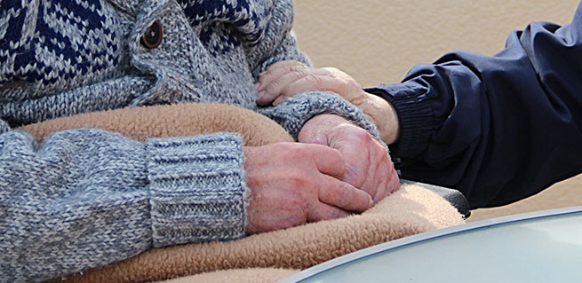 Bild på två äldre personer, ena personer håller handen om den andras arm