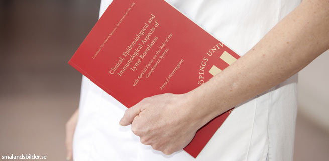 Bild på en person som håller i en röd bok