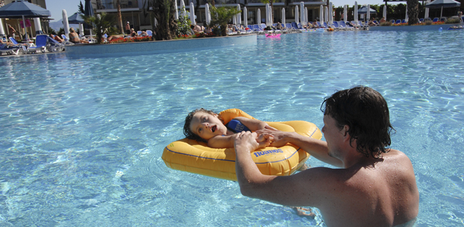 En flicka badar i en pool tillsammans med en vuxen. 