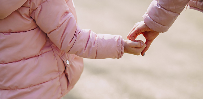 Ett barn håller en vuxen i handen.