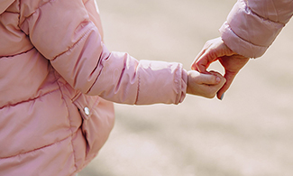 Ett barn håller en vuxen i handen.