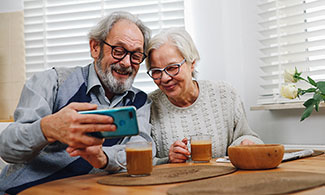 Bild på ett äldre par som tittar på en mobiltelefon.