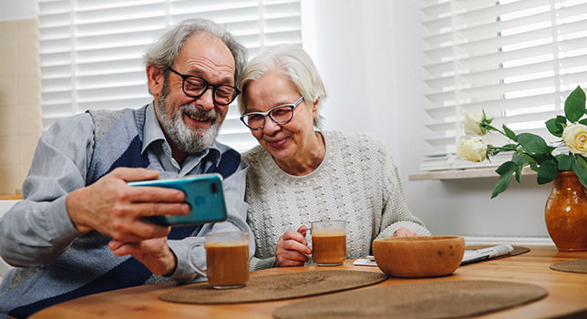 En man och en kvinna tittar på en mobiltelefon och ler.