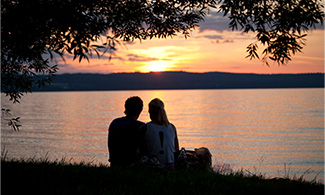 Ett par tittar på solnedgång vid en sjö